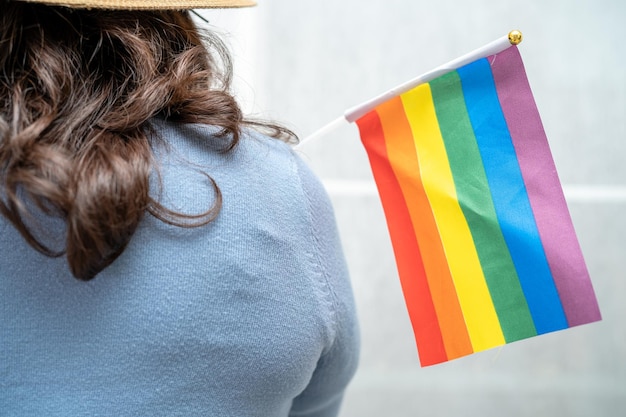Lgbtプライド月間のレインボーフラッグハートシンボルを持つアジアの女性は、ゲイレズビアンバイセクシュアルトランスジェンダー人権の6月の社会の毎年恒例を祝います