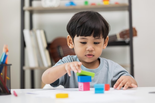 家庭からのアジアの小さな男の子の教育幼稚園に入る前に学ぶ子供たちの成長木のおもちゃで遊んだり、絵を描いたり、絵を描いたりするスキルを練習します