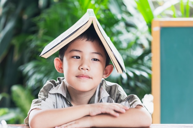 Asian little boy holding book on head education concept