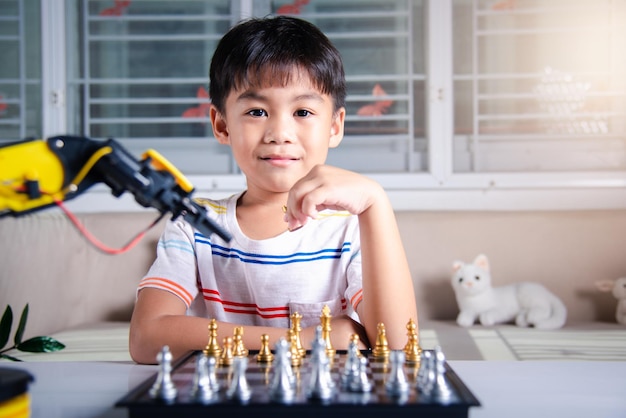 아시아 소년이 로봇 기계 팔로 체스를 하고 있다