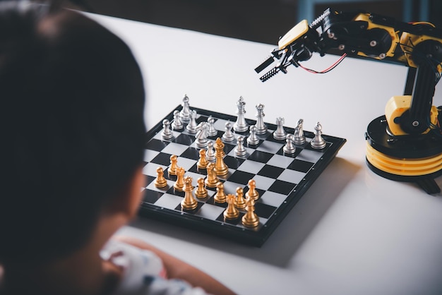 Asian little boy is playing chess with robot machine arm