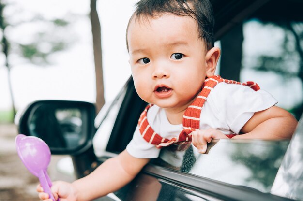 アジアの小さな男の子が車から覗きます。