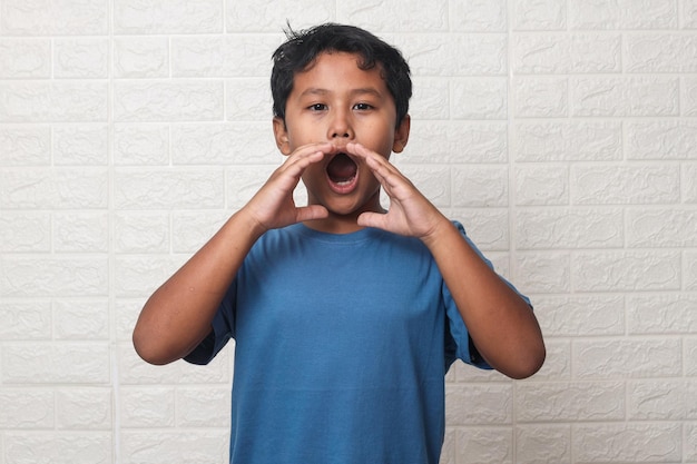 Asian little boy shouting excited to front over white background