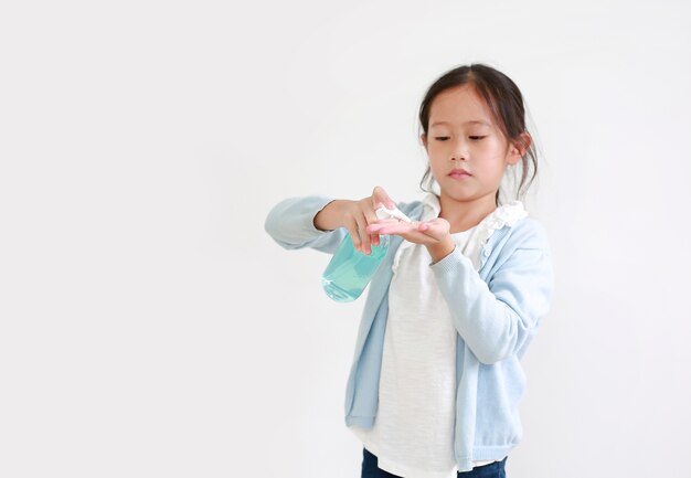 Asian little child applying alcohol gel from plastic bottle for cleaning hand for hygiene