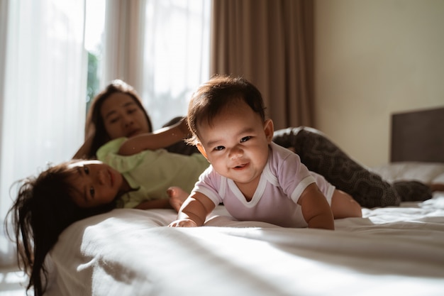 Азиатские маленькие дети лежат в постели с мамой рядом с ними