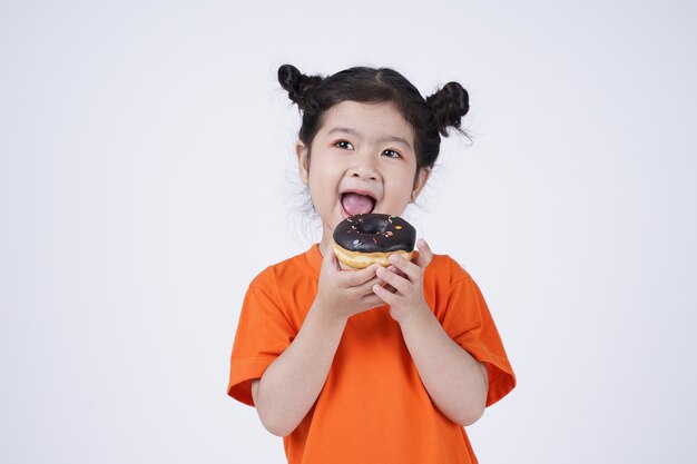 Asian little cute girl eating big donut isolated on white