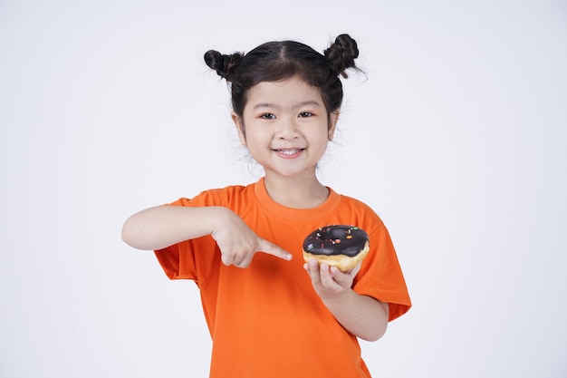 Asian little cute girl eating big donut isolated on white