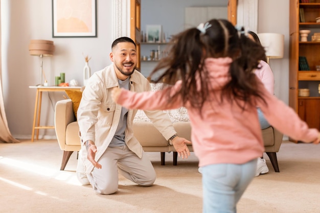 Asian little daughter running to embrace daddy at home