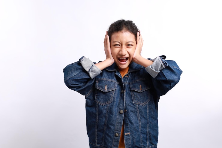 Photo 평범한 스타일의 아시아 소녀가 화를 내고 색 배경에 슬픈 표정을 보이고 있습니다.