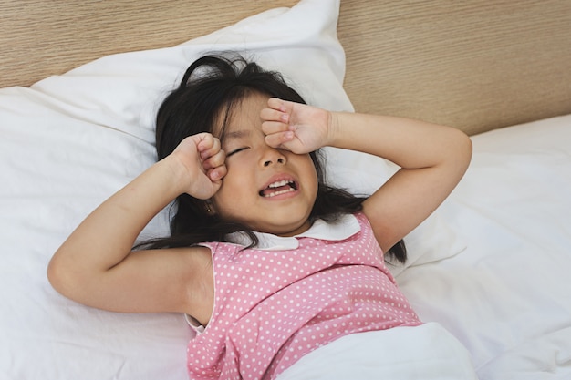 Asian little girl crying on bed 