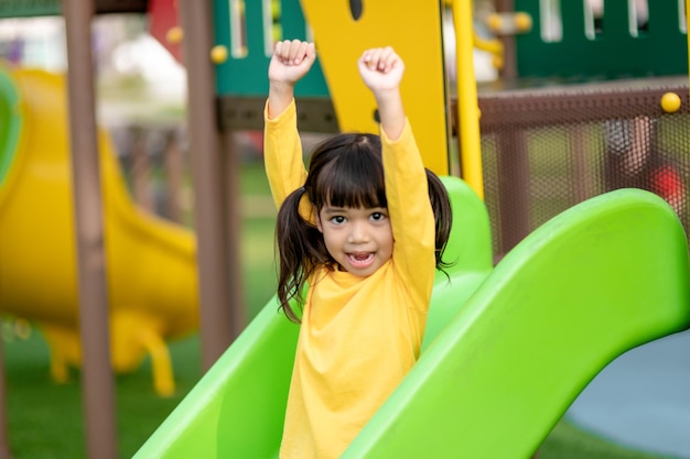 アジアの少女は子供の遊び場で遊ぶことを楽しんでいます屋外の肖像画