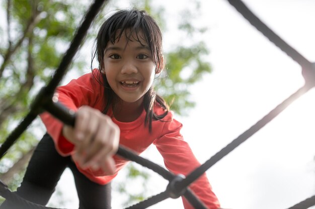 アジアの少女は子供の遊び場で遊ぶことを楽しんでいます屋外の肖像画