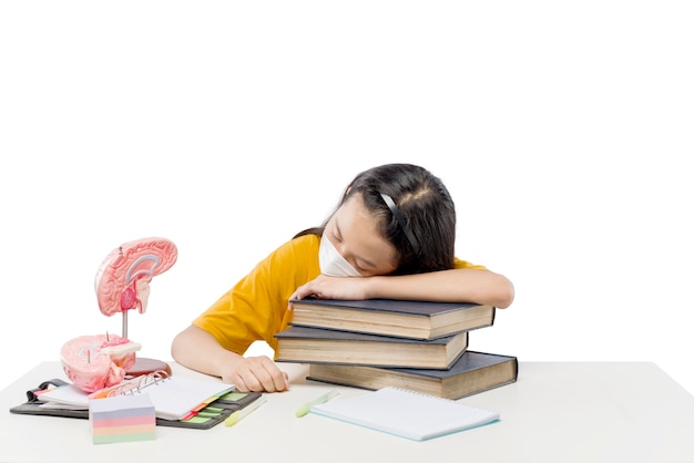 Asian little girl falls asleep while learning from home isolated over white background. Online education during quarantine