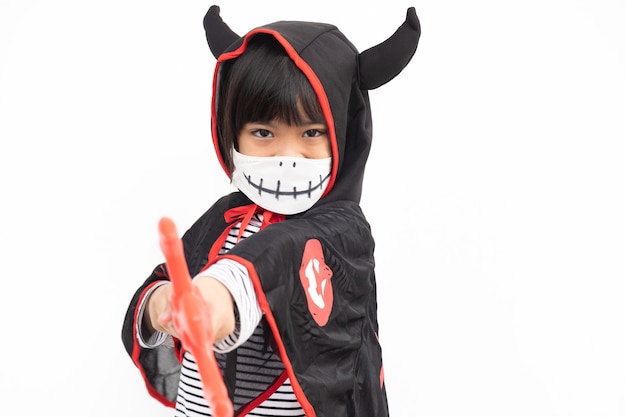 Азиатская маленькая девочка в костюме Хэллоуина в медицинской маске. Хэллоуин с мерами безопасности от Covid-19