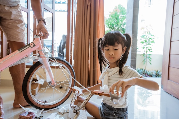 新しい組み立てられていないミニ自転車のハンドルバーを保持しているアジアの少女