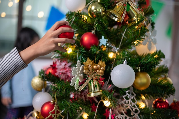 Азиатская маленькая девочка украшает елку и наслаждается Рождеством