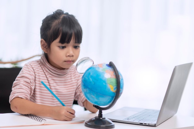 Asian little girl is learning the globe model concept of save\
the world and learn through play activity for kid education at\
home