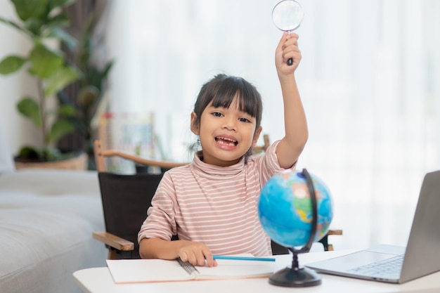 Asian little girl is learning the globe model concept of save\
the world and learn through play activity for kid education at\
home