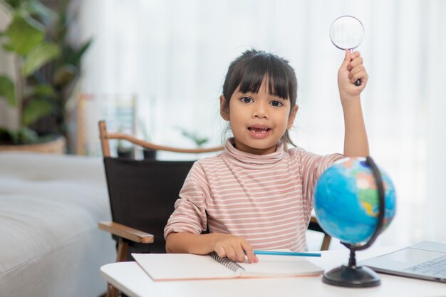 Asian little girl is learning the globe model concept of save the world and learn through play activity for kid education at home