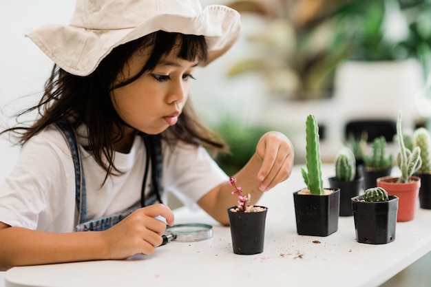 アジアの少女は、就学前の子供のための植物成長学習活動と自然の木のための子供の教育の家の概念で植物を植えています