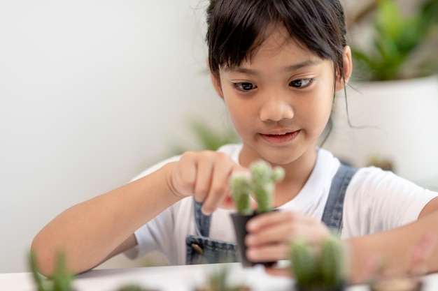 アジアの少女は、就学前の子供のための植物成長学習活動と自然の木のための子供の教育の家の概念で植物を植えています