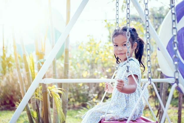 Asian little girl is swinging in the backyard