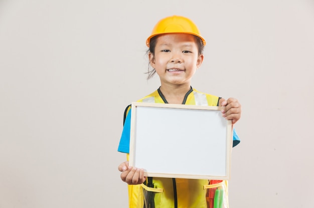 Foto bambina asiatica o bambini in camicia blu e casco giallo in piedi e tenendo in mano la lavagna