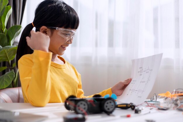 電気自動車システムを学ぶアジアの少女エコフレンドリーな代替エネルギーのコンセプト