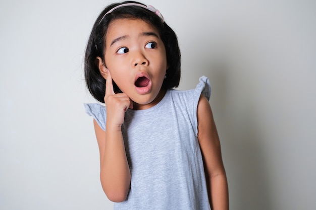 Азиатская маленькая девочка смотрит в сторону с подозрительным выражением лица
