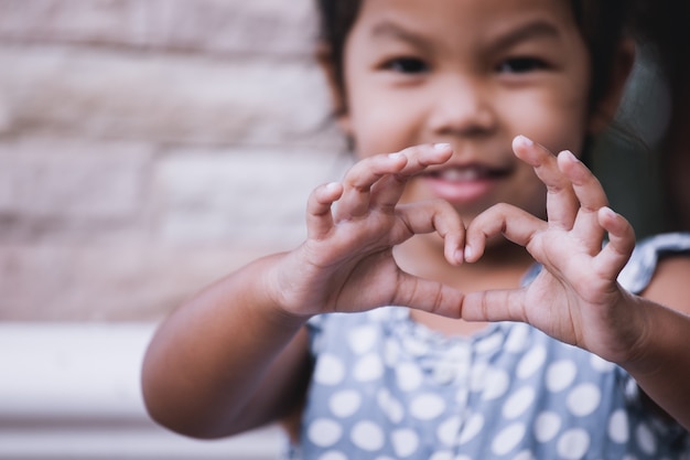 Photo asian little girl making heart shape with hands in vintage color tone