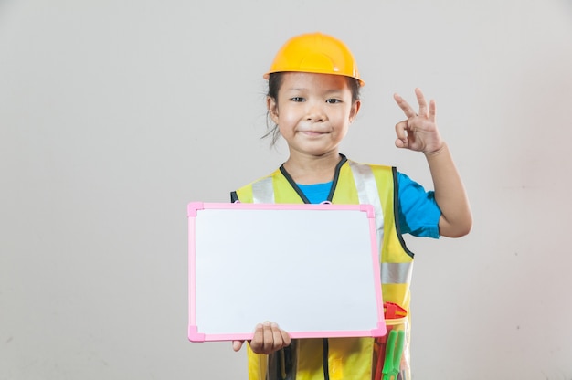 사진 파란색 셔츠와 노란색 안전모 서와 화이트 보드를 손에 들고 아시아 어린 소녀 또는 아이