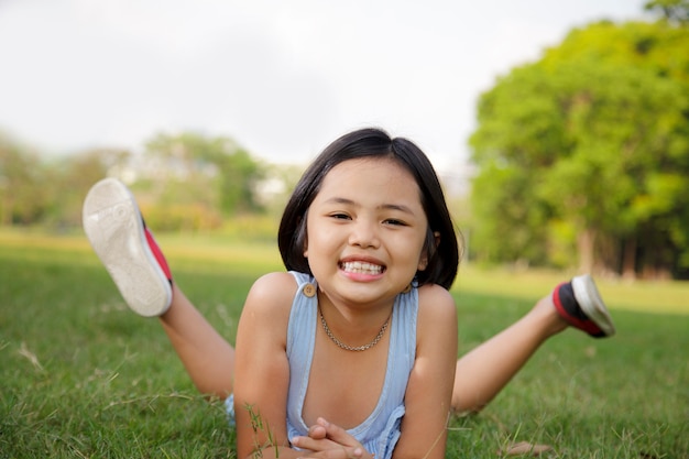 La bambina asiatica si rilassa e sorridendo felicemente nel parco