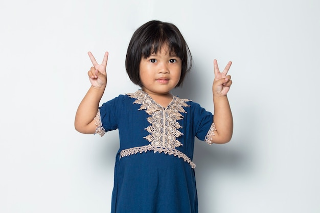 흰색 배경에 고립 된 평화 또는 승리 손 제스처를 보여주는 아시아 어린 소녀