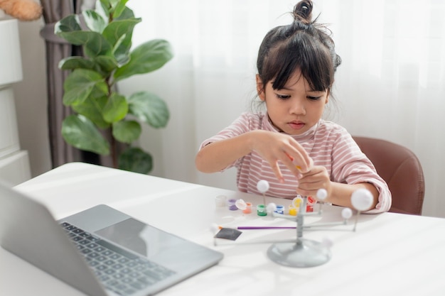 Asian Little girl studies the solar system in geography class looking at the scale model of planets