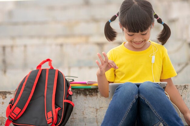 Bambina asiatica che prende lezione in linea e felice