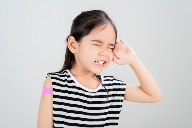 Asian little girl wear glasses showing her arm with bandage after virus