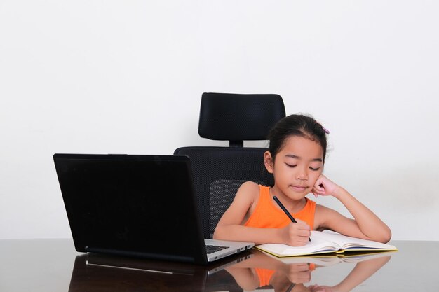 Asian little girl writting something in a book when study