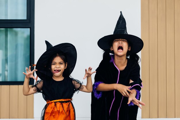 Азиатские маленькие девочки в костюмах на Хэллоуин веселятся дома