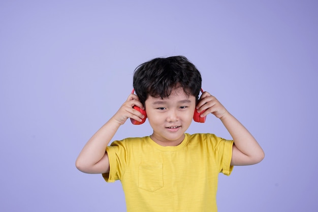 音楽を聴いてヘッドフォンでアジアの小さなハンサムなかわいい男の子