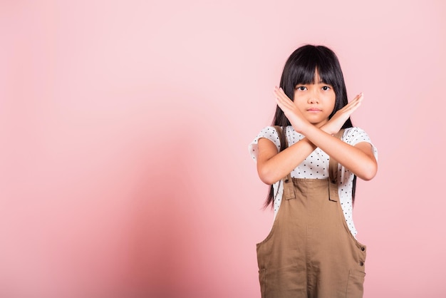 Asian little kid 10 years old showing two hands cross arms say no X sign