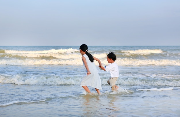 Asian little kid boy and girl having fun on sea beach in summer