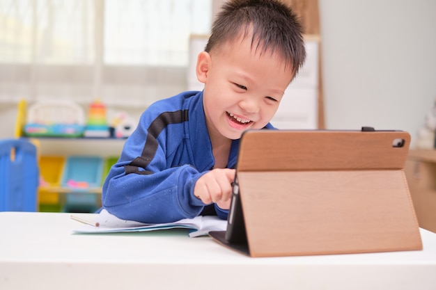집에서 자신의 온라인 수업 중 숙제를 공부하는 노트북 컴퓨터를 사용하는 아시아 작은 남학생 아이