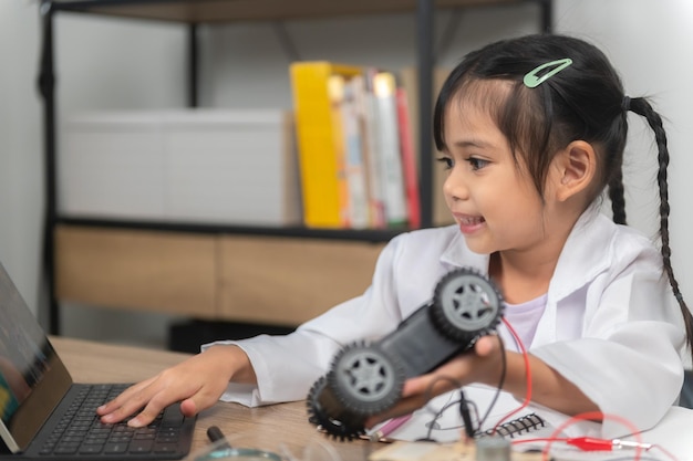 STEM クラスでロボットを構築およびコーディングするアジアの小さな女の子固定および修理メカニックのおもちゃの車