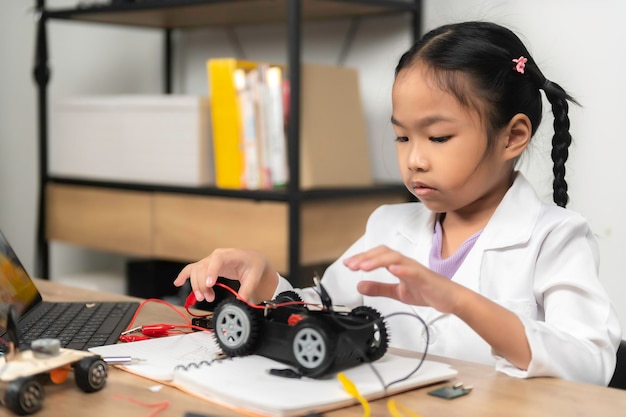 STEM 수업에서 로봇을 만들고 코딩하는 아시아의 작은 소녀기계공 장난감 자동차 수리 및 수리