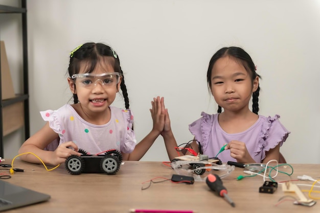 Asian littlle girl constructing and coding robot at STEM classFixing and repair mechanic toy car