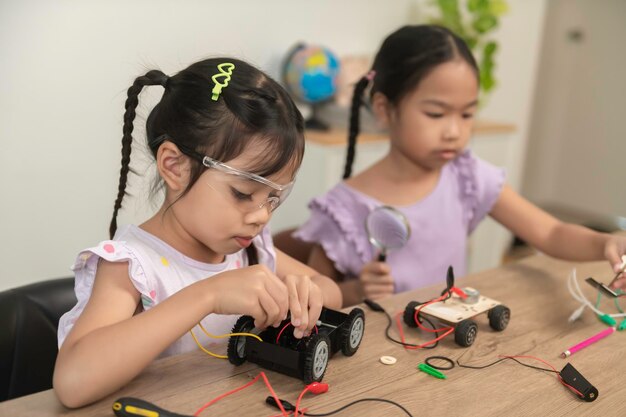 아시아 소녀가 STEM 수업에서 로을 만들고 코딩합니다. 장난감 자동차를 수리하고 수리합니다.