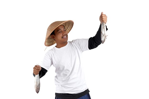 An Asian local fisherman standing in front white background. Holding some fish and smile. Close Up