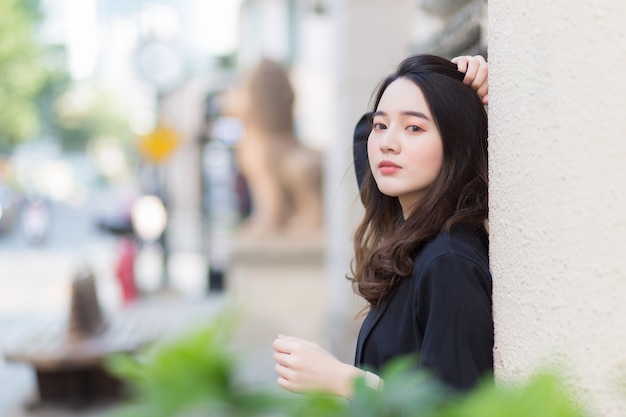 Asian longhaired beautiful girl in a dark blue robe is looking out and standing outdoors