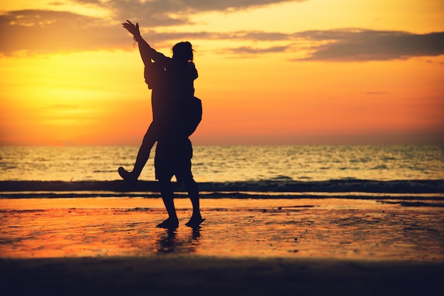 Amanti asiatici felici sulla spiaggia con un bel tramonto