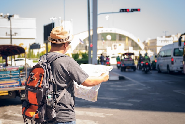 Asian male backpack tourists Standing on the road and holding a map